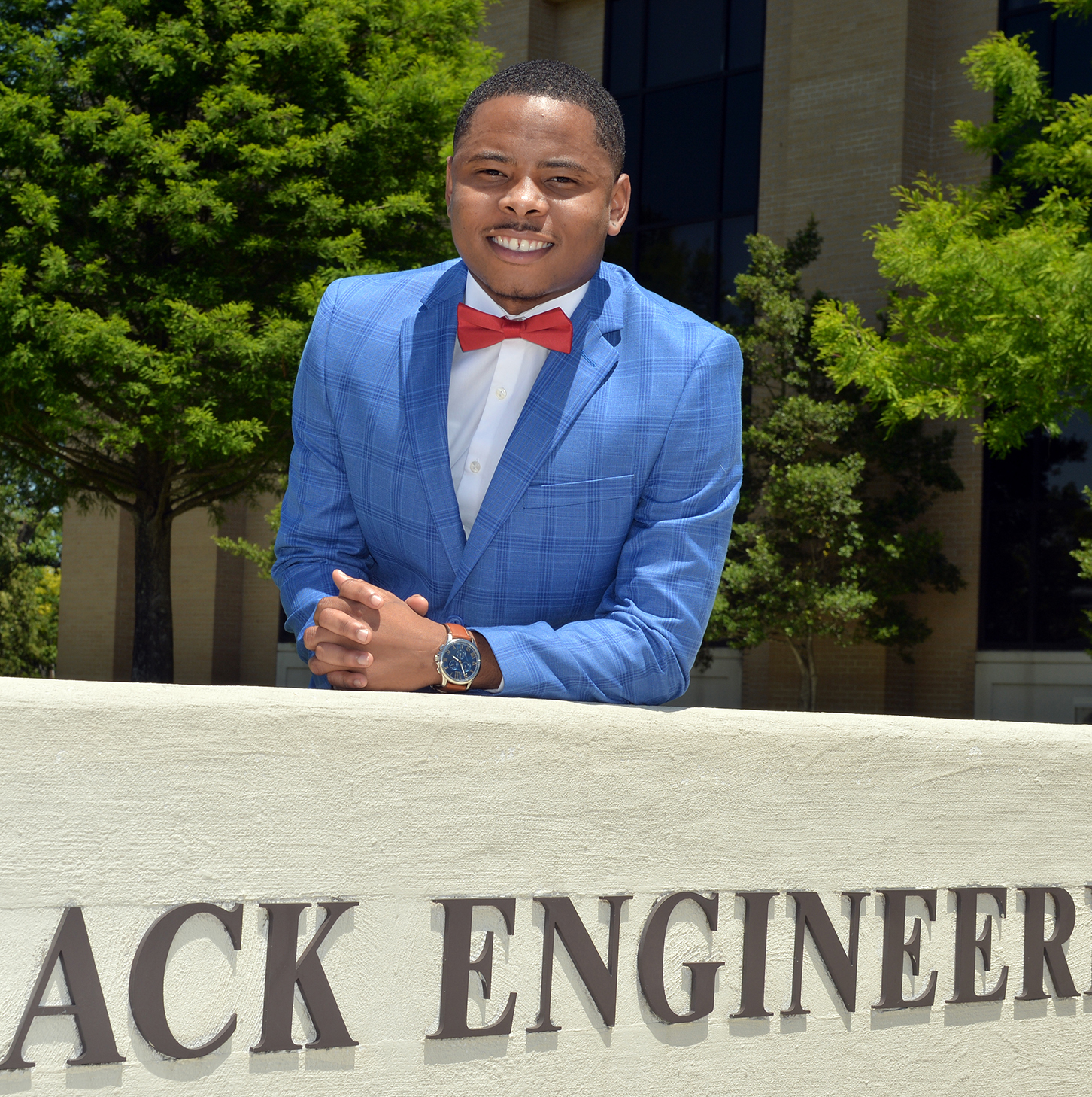 Chief student marshal standing by Engineering Building sign outside.